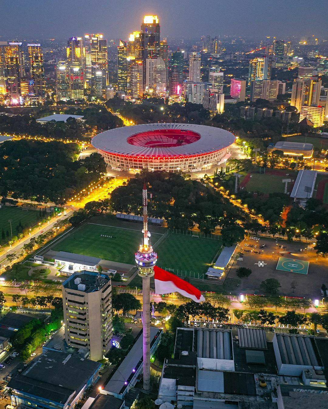 Jakarta skyline with Indonesian flag and Gelora Bung Karno Stadium at dusk
